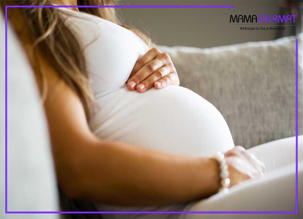 نگرانی‌های دوران بارداری تصویر شکم خانم باردار نشسته بر روی مبل