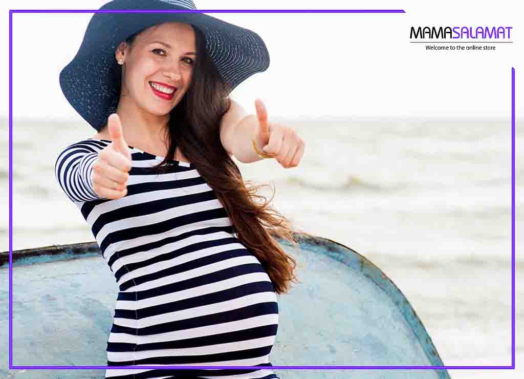 حفظ زیبایی در دوران بارداری خانم باردار با کلاه و شاد در کنار دریا 
