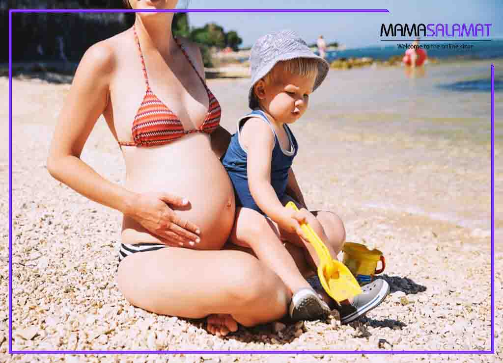 ضد آفتاب مناسب بارداری خانم باردار کنار ساحل به همراه فرزند کوچکش